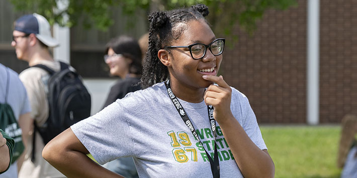 photo of a student standing and smiling outside on campus