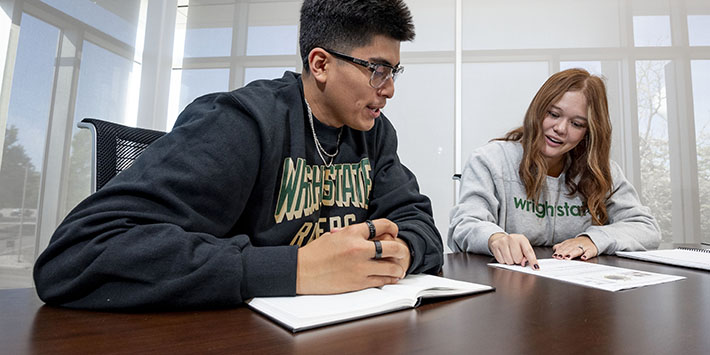 photo of two students sitting at a table and talking 