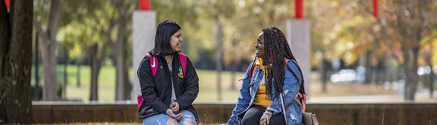 photo of two students sitting outside on campus