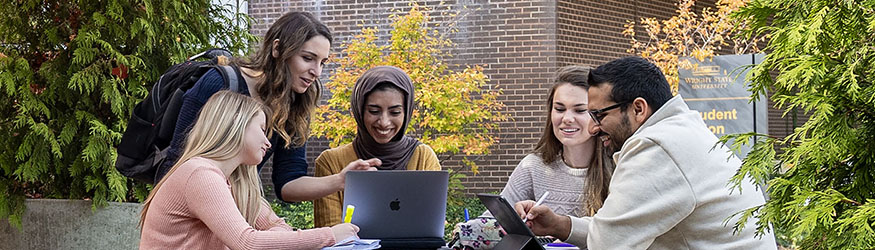 photo of students sitting at a table outside on campus