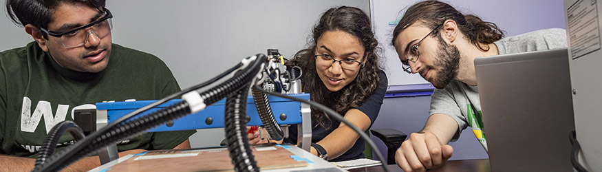 photo of three students working on an engineering project in a lab