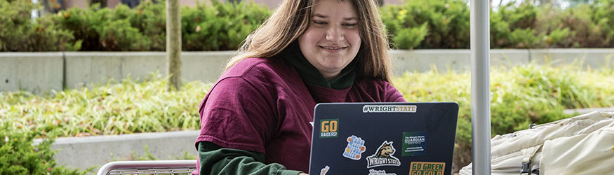 photo of a student sitting outside using a laptop
