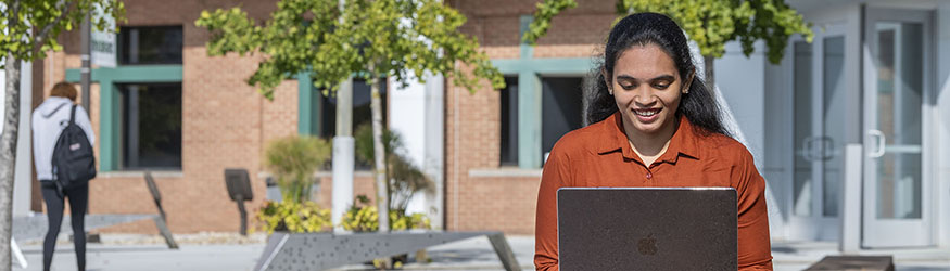 photo of a student using a laptop outside on campus